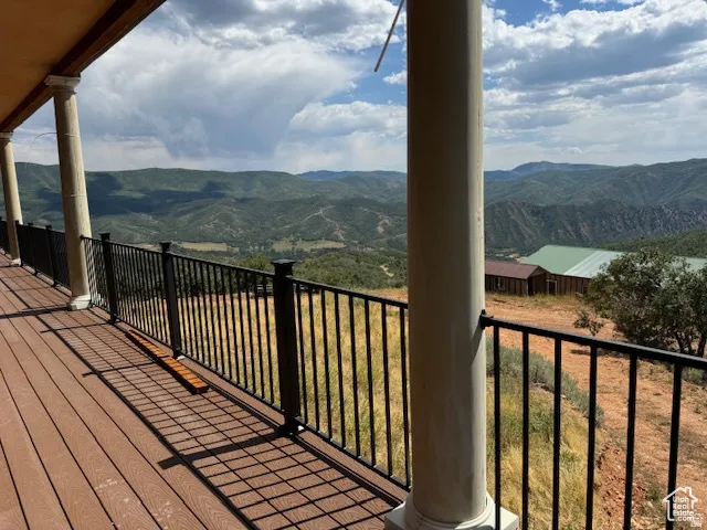 Expansive outdoor deck featuring wood-finish flooring, classic white columns, and black metal railings