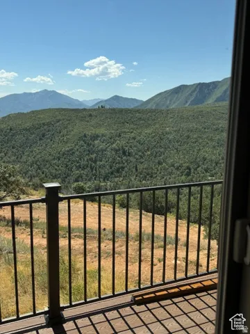 Outdoor decking with composite wood-finish material and black metal railing, offering expansive mountainous terrain and distant tree lines