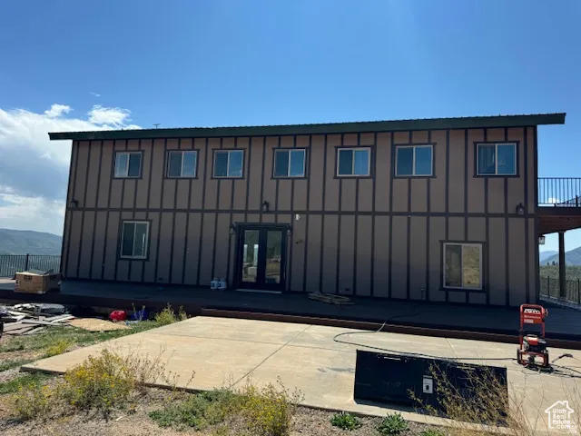 Two-story exterior with board and batten siding, multiple windows, and a dark double-door entry