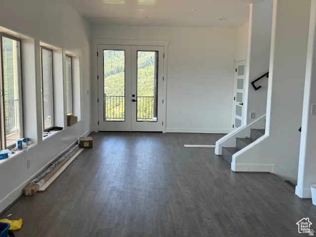 Spacious room featuring wood-finish flooring, white walls, and a series of three large windows providing abundant natural light