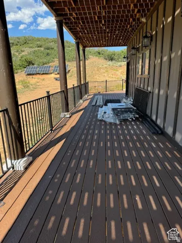 Expansive covered deck featuring composite decking, dark bronze columns, and black metal railings