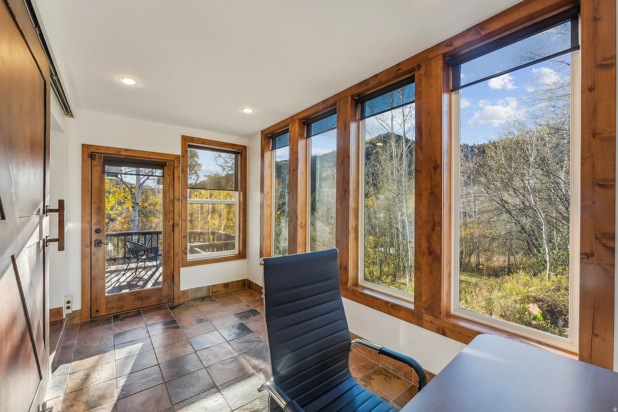 Interior space featuring large picture windows with wood framing, recessed lighting, and multi-toned tile flooring