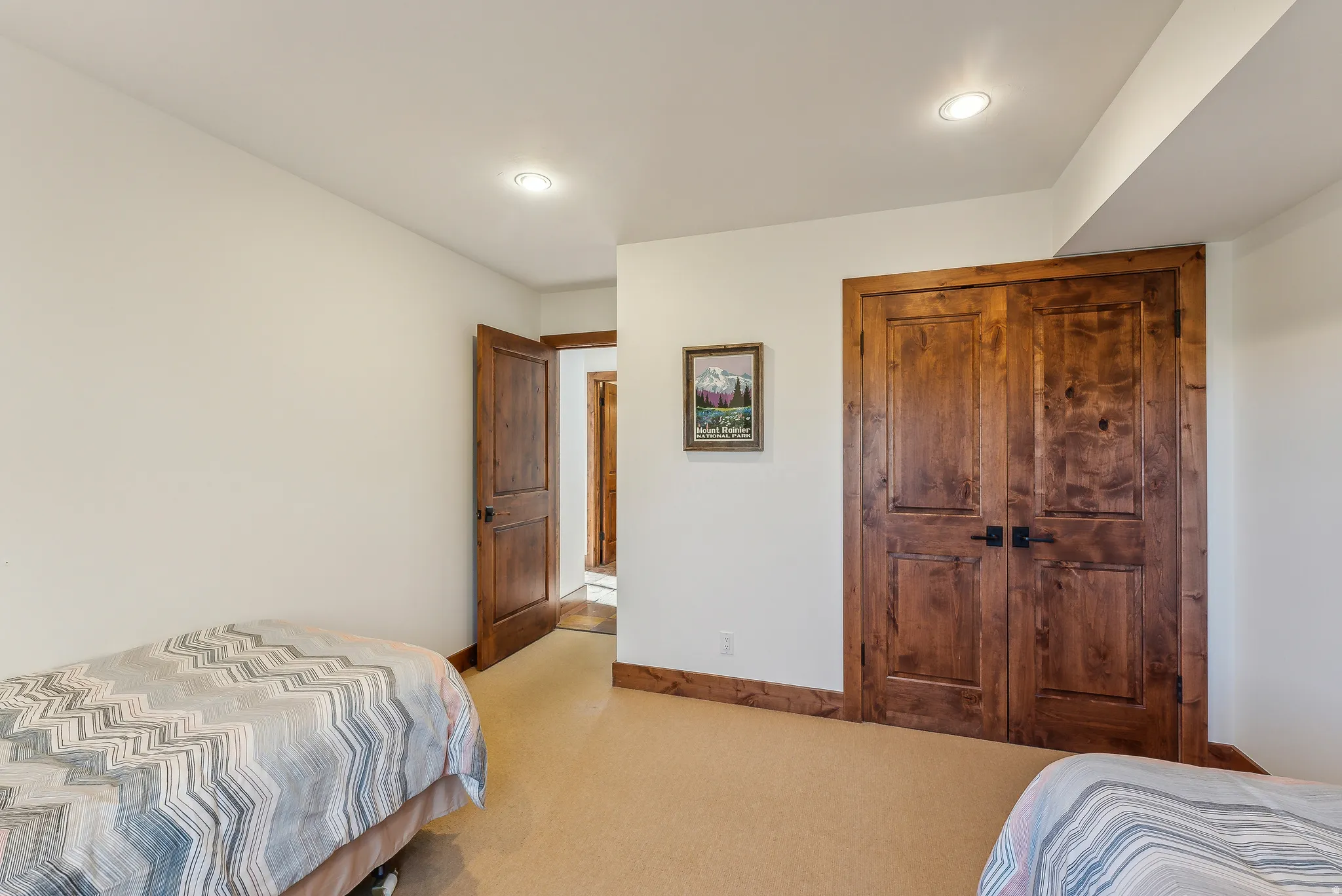 Spacious room featuring rich wood-finish doors with black hardware, complementing wood-finish trim, recessed lighting, and light-toned wall finishes
