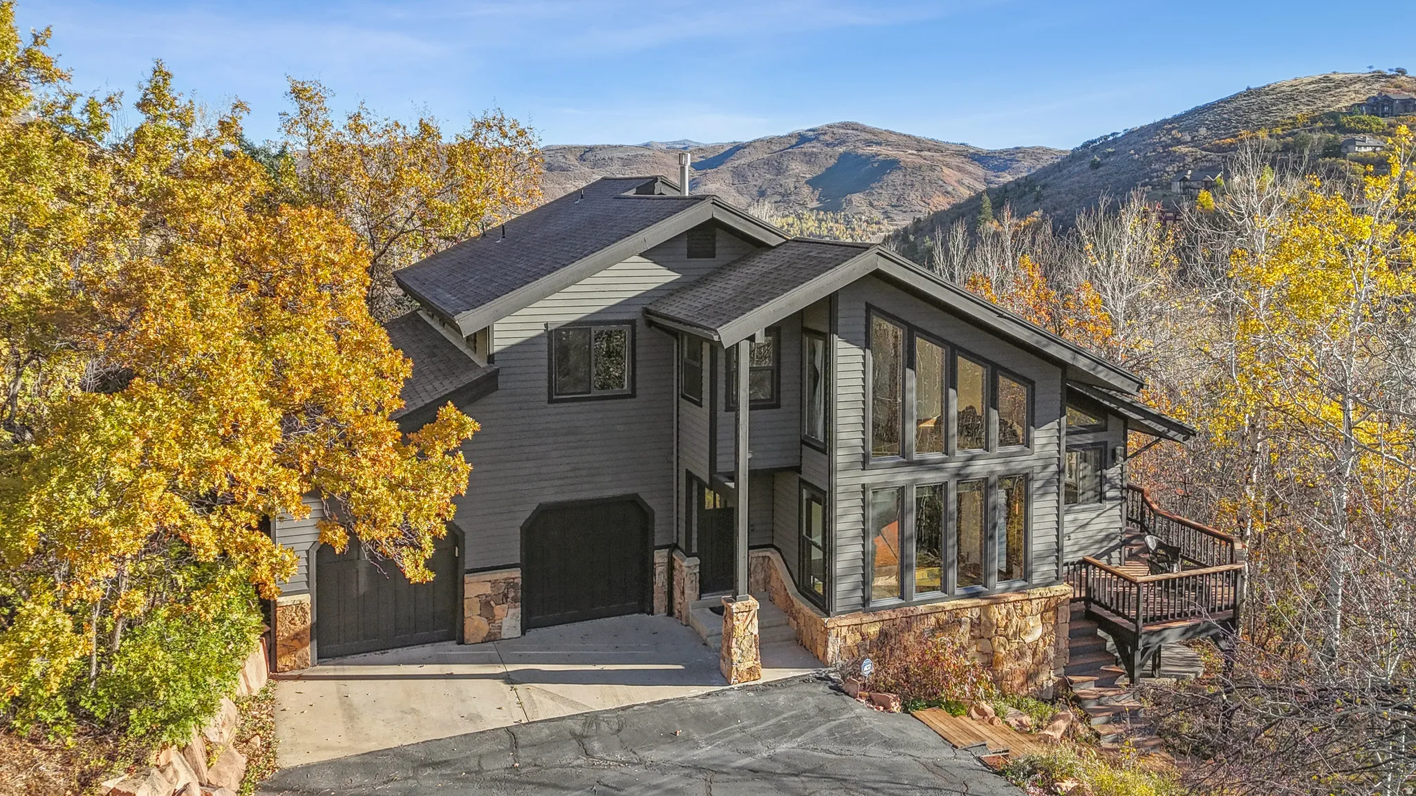 Contemporary-style residence featuring vertical siding, stone accents, and a multi-level deck