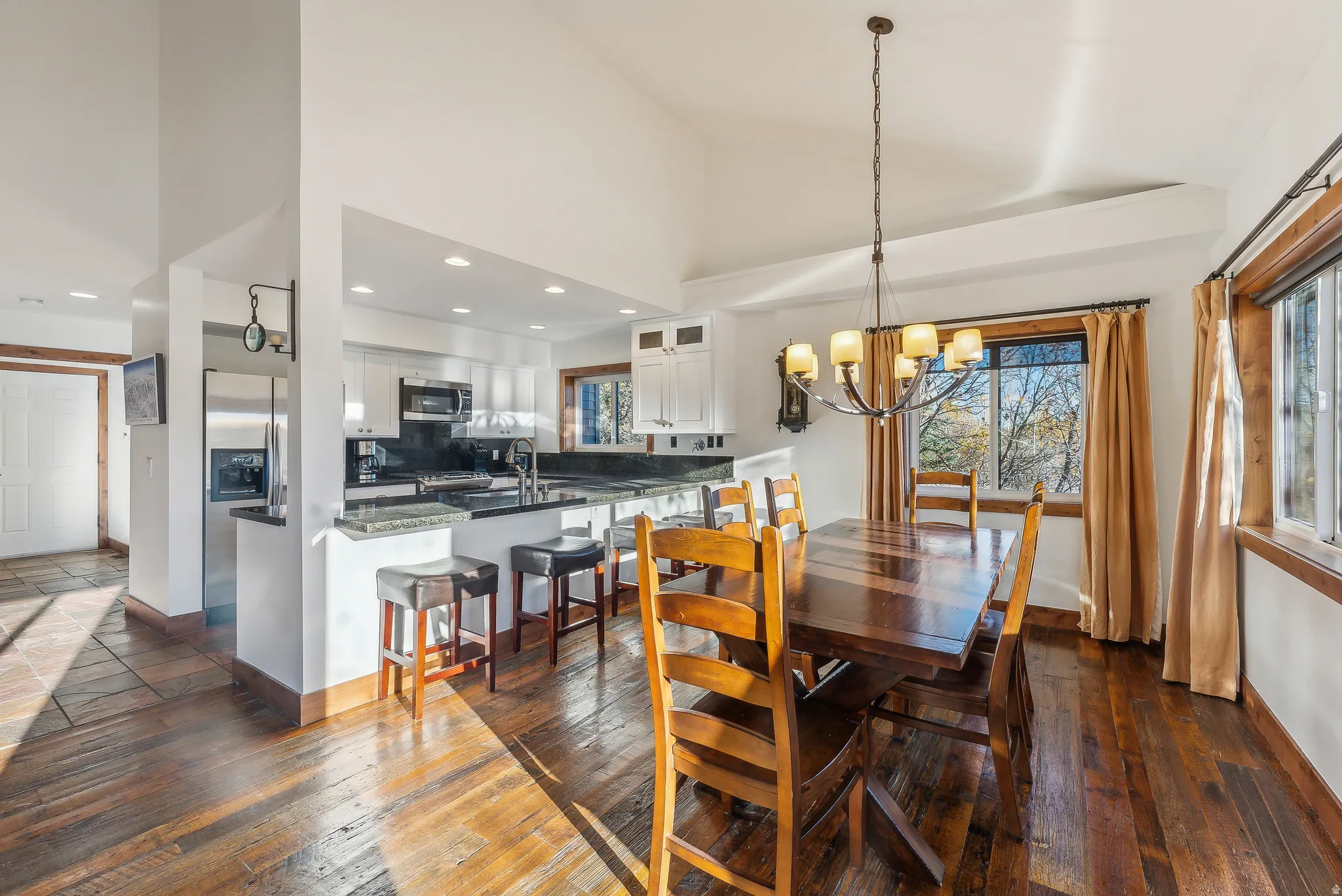 Open-concept kitchen and dining area featuring wood-finish flooring, vaulted ceilings, and recessed lighting