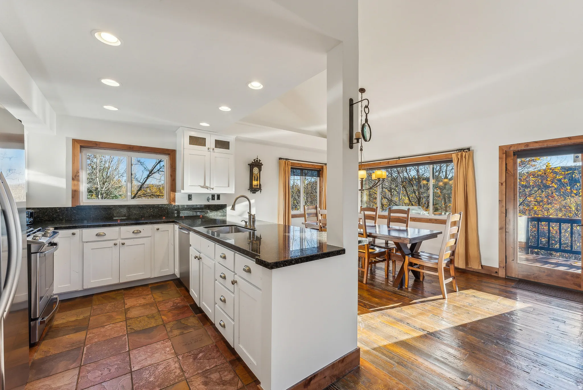 Kitchen featuring white cabinetry, dark stone countertops, stainless steel appliances, and multi-toned tile flooring