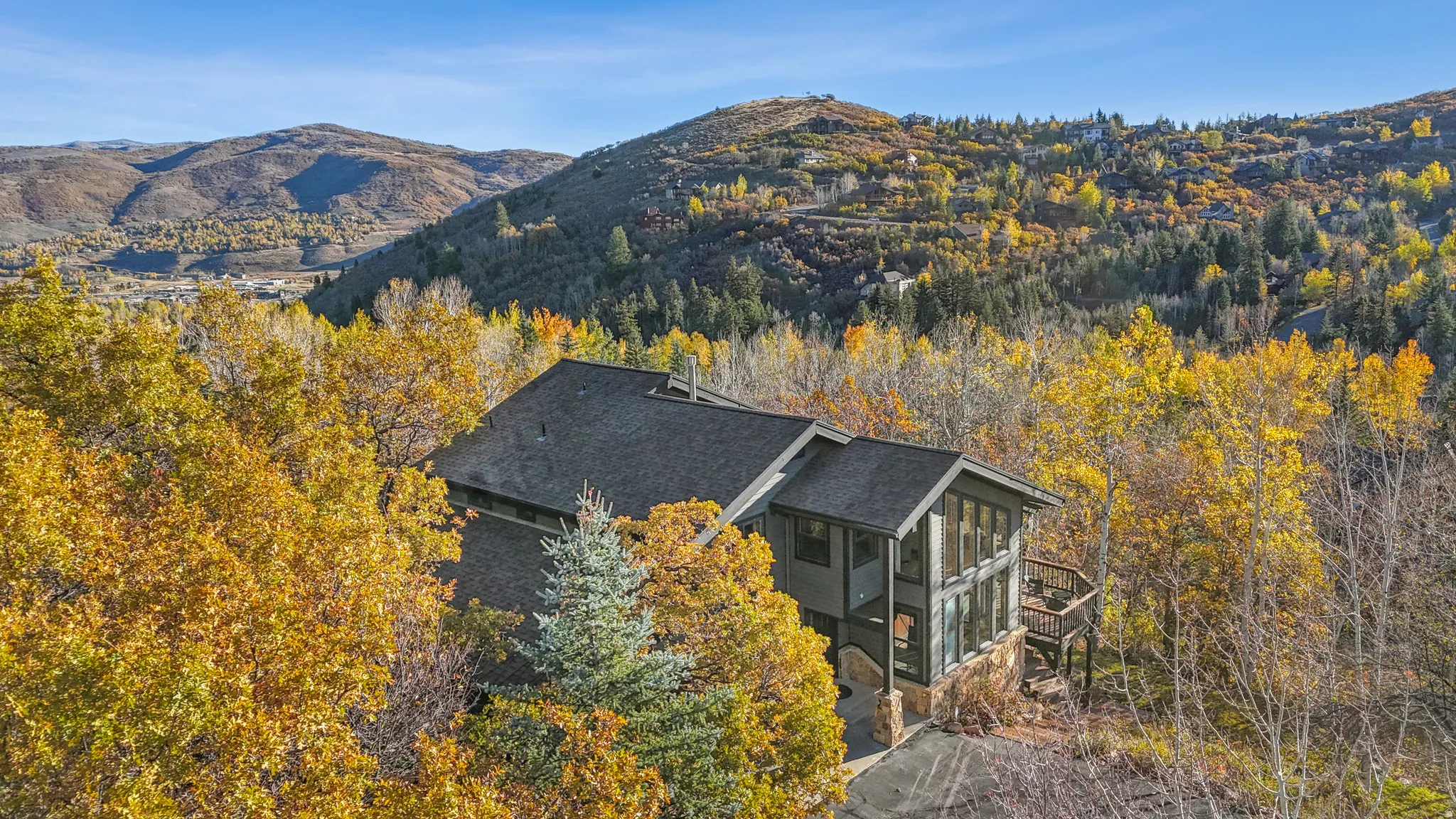 Multi-level home featuring a dark shingle roof and a stone foundation
