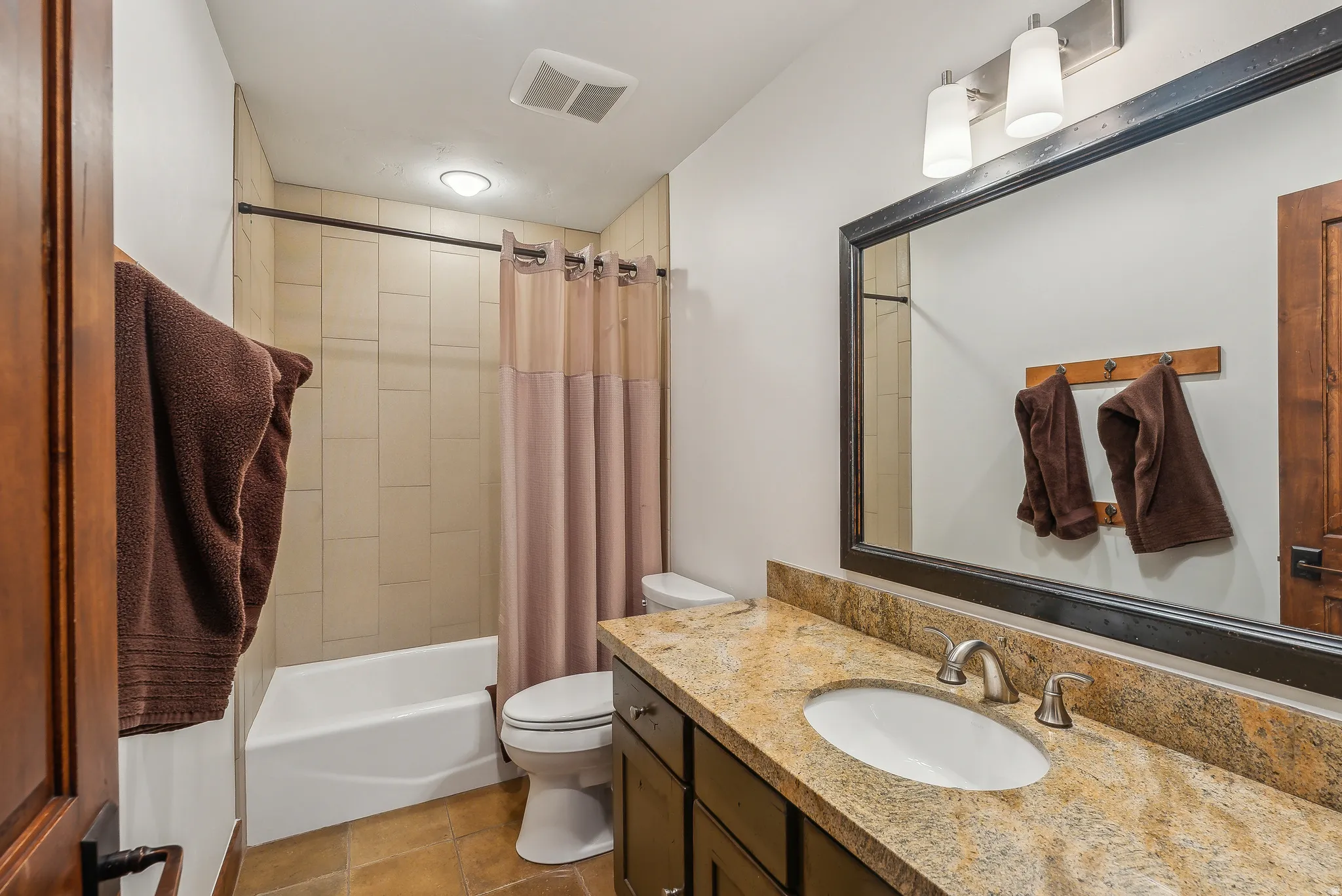 Bathroom featuring a vanity with an oval sink, brushed nickel faucet, and a granite-finish countertop