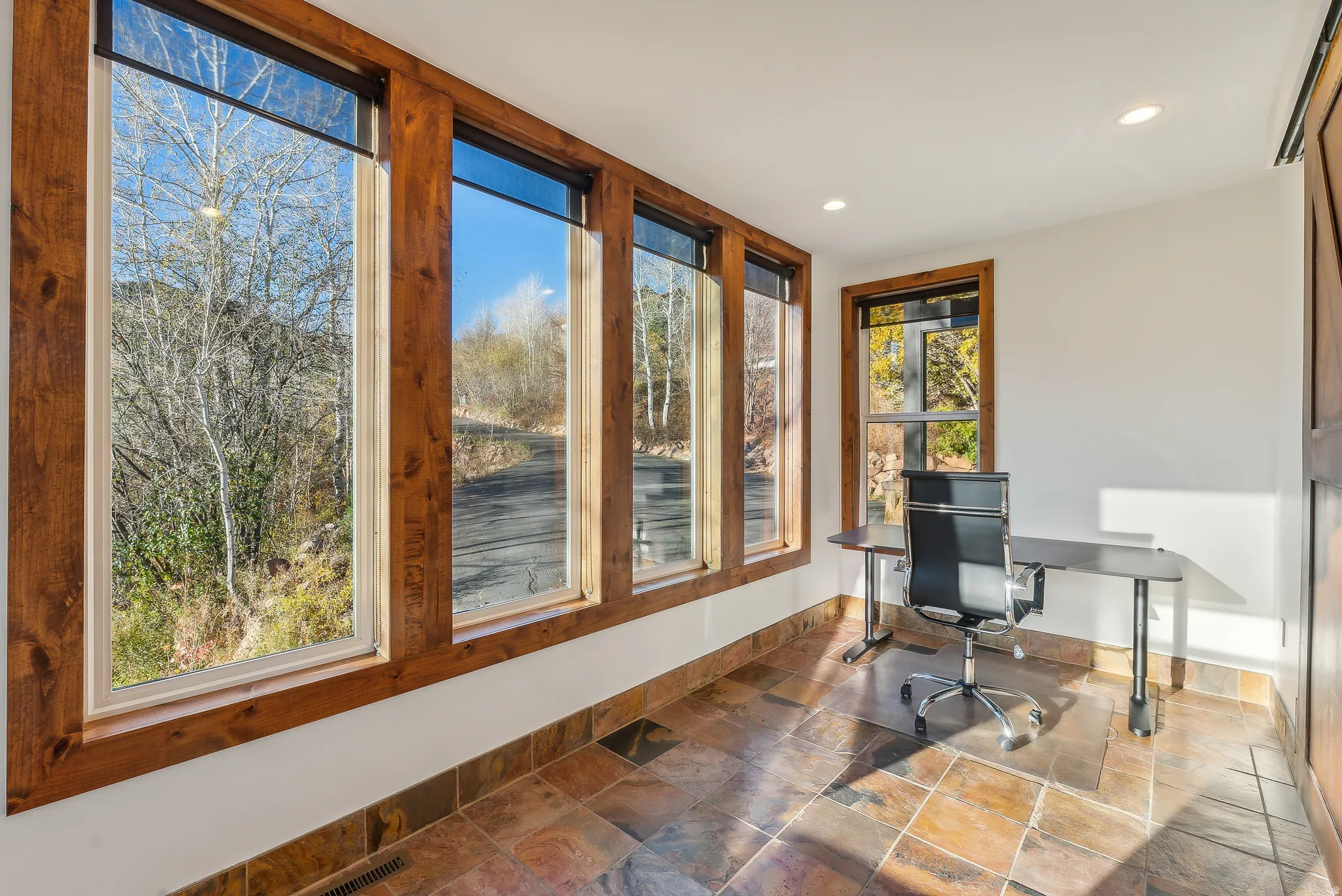 Room with multiple windows featuring natural wood trim and slate-finish tile flooring