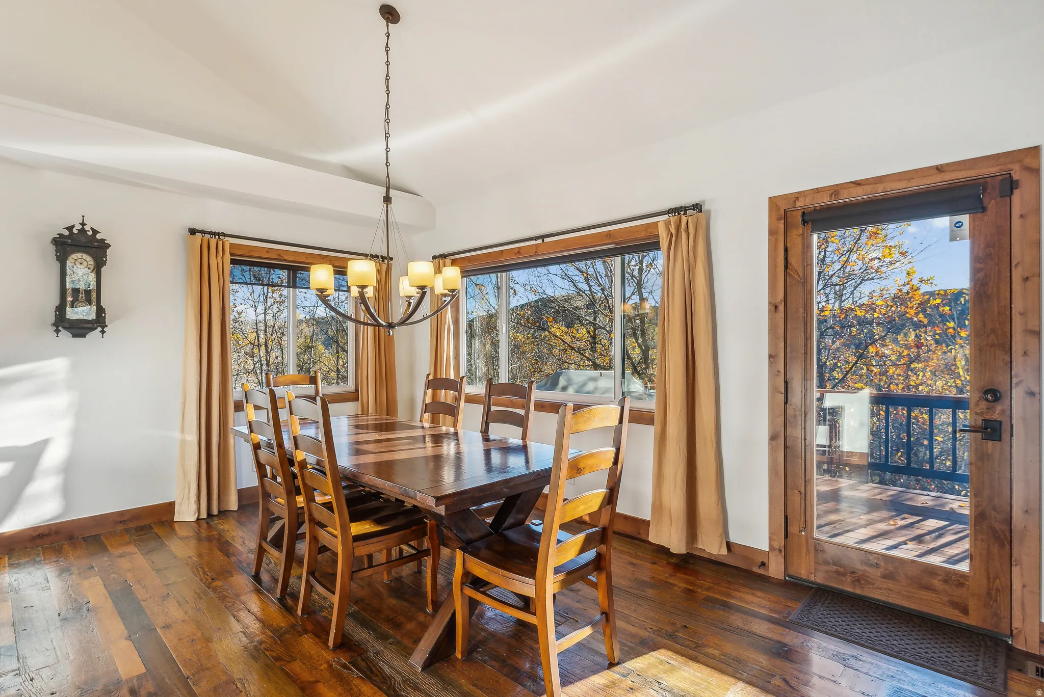 Dining area featuring wood-finish flooring, a contemporary chandelier, and a wood-framed glass door leading to an outdoor balcony