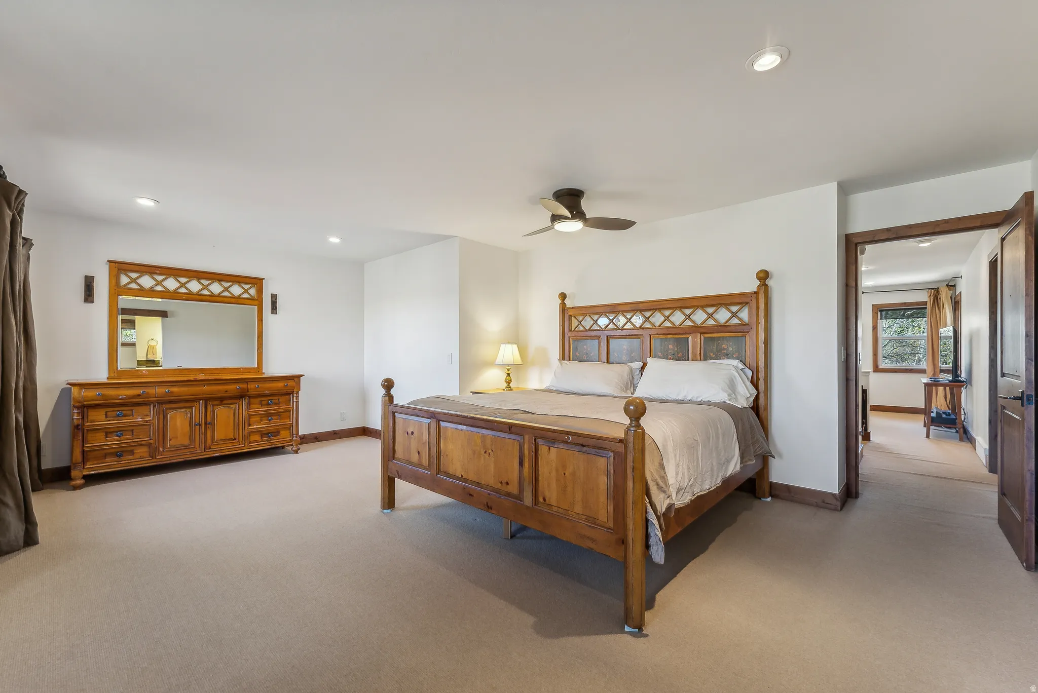 Spacious room featuring neutral carpeting, white walls, recessed lighting, and a ceiling fan