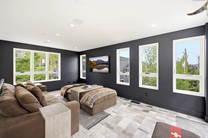 Spacious room featuring multiple white-framed windows, dark accent walls, and recessed lighting
