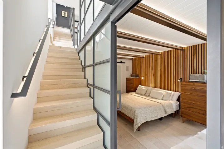 Light wood-finish staircase with integrated wall lighting and a sleek black handrail