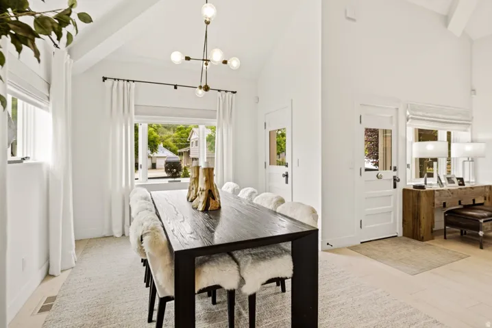 Vaulted ceilings illuminate the dining area, featuring a dark wood-finish table and a contemporary sputnik chandelier