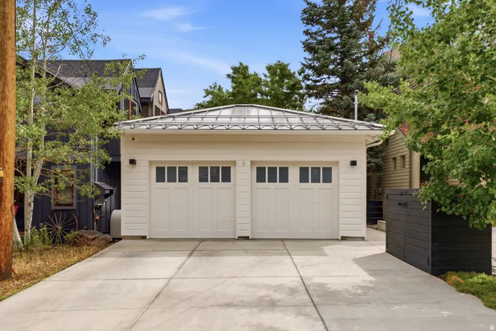Two-car garage featuring white paneled doors with upper window inserts, white horizontal siding, and a standing seam metal roof