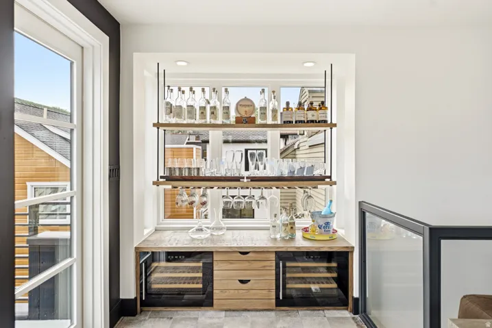 Built-in beverage station featuring a light wood-finish countertop, dual under-counter beverage refrigerators, and two storage drawers