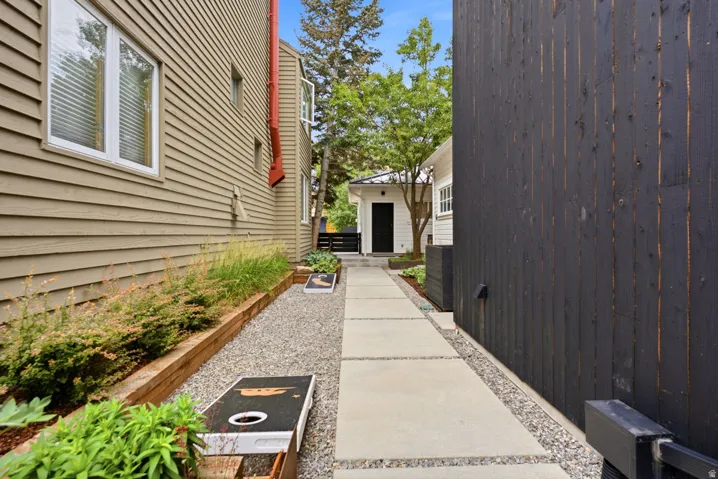 Exterior walkway featuring concrete pavers, gravel accents, and mature landscaping
