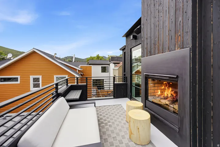 Outdoor patio featuring an integrated fireplace with a glass enclosure, horizontal metal railings, and patterned paver flooring