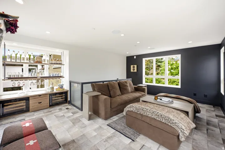 Integrated wet bar featuring wood-finish cabinetry, dual beverage refrigerators, and shelving