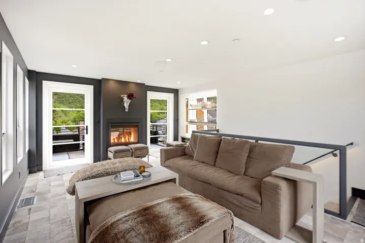 Living area featuring a modern fireplace, white trim windows, recessed lighting, and light-toned tile flooring