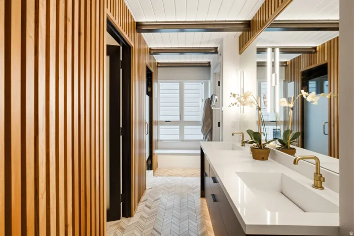 Double vanity with integrated sinks, brass-finish faucets, and a full-width mirror