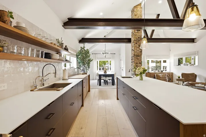 Modern kitchen featuring two islands with white countertops, dark wood-finish cabinetry, and light wood-finish flooring