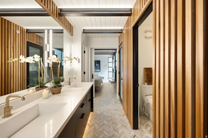 Double vanity with integrated sinks, brushed gold faucets, and a large mirror