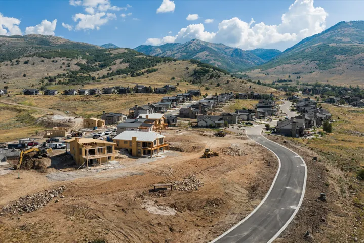 Mountainous terrain surrounds a developing residential community featuring a paved, winding road