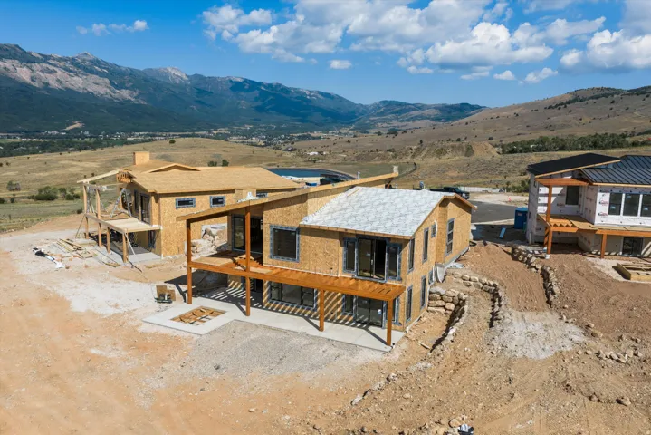 Property under construction featuring a multi-level design with extensive framing, multiple window openings, and a prominent mountain backdrop