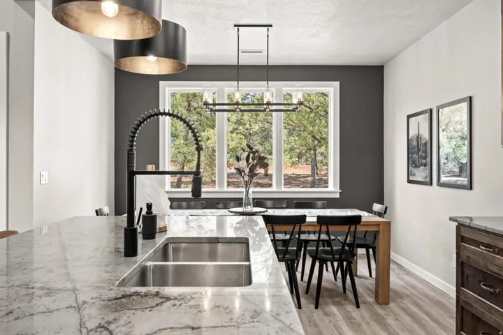 Kitchen island featuring a dual basin stainless steel sink with a matte black pull-down faucet and a stone countertop