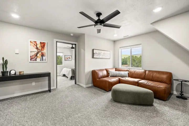 Spacious room featuring light gray walls, recessed lighting, a modern ceiling fan, and gray textured carpeting throughout