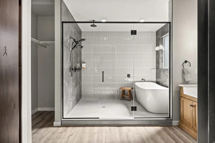 Contemporary bathroom featuring a spacious glass-enclosed shower, freestanding soaking tub, and natural wood-finish flooring
