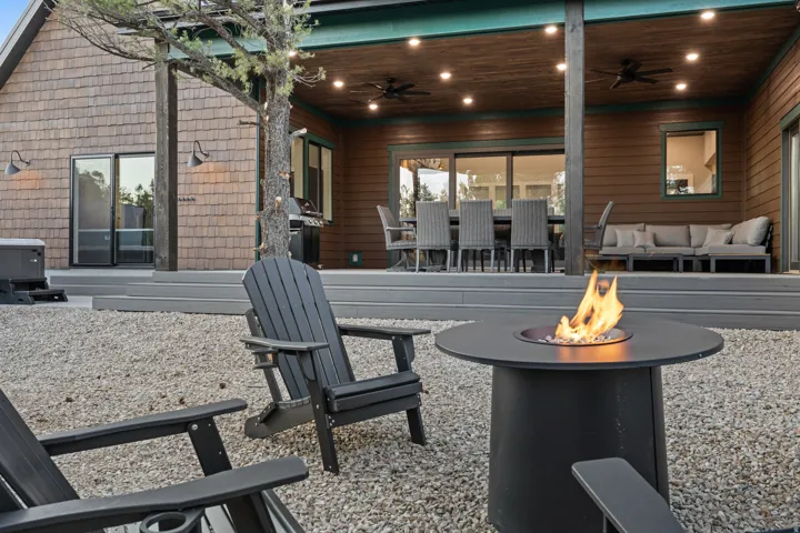 Outdoor living area featuring a fire pit, expansive composite decking, and a covered patio with recessed lighting and ceiling fans