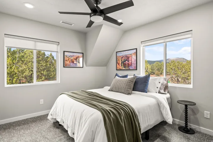 Bright room featuring dual windows with natural scenery, a ceiling fan, and recessed lighting and ensuite bathroom