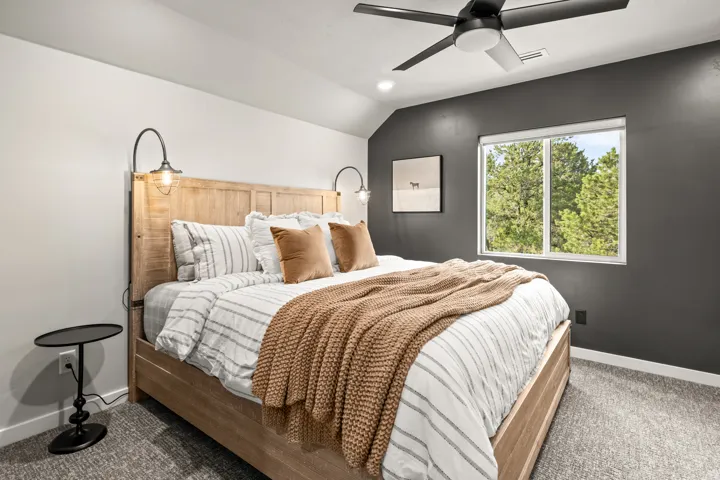 Carpeted room featuring a ceiling fan, wall-mounted light fixtures, and ensuite bathroom