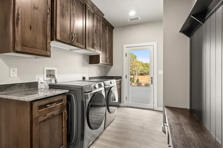 Laundry room with washer, dryer, cabinetry and bench