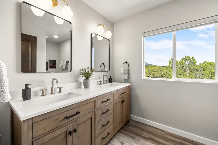 Hall bathroom with dual vanity with wood-finish cabinetry, white countertops, and undermount sinks