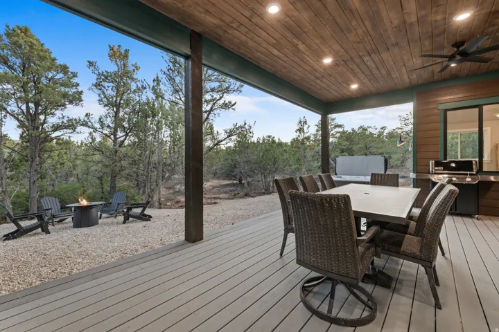 Expansive outdoor living area featuring a wood-finish plank ceiling with recessed lighting, a ceiling fan, and composite decking