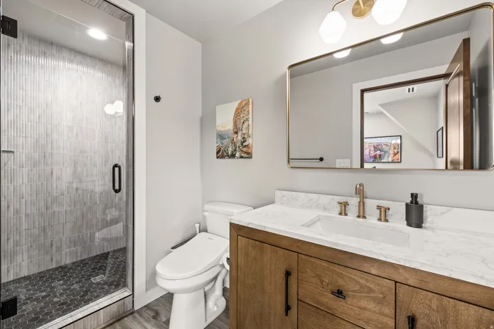 Modern bathroom featuring a glass-enclosed shower with vertical tile surround and hexagonal floor tiles