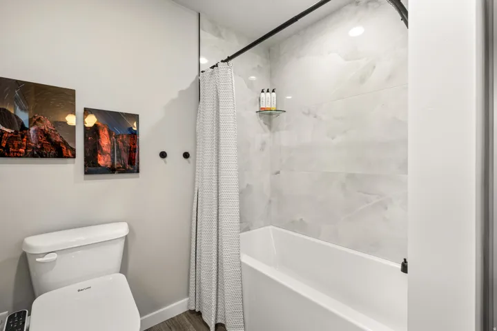 Hall bathroom featuring a white bathtub, light-toned wall tiling, and overhead recessed lighting