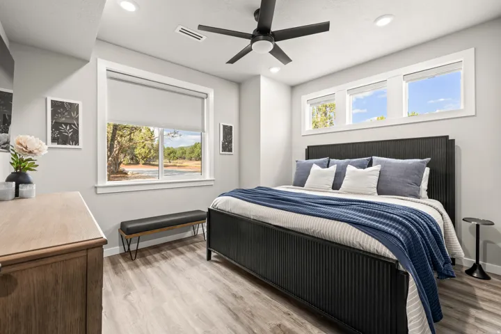 Well-lit sleeping quarters featuring recessed lighting, a ceiling fan, multiple windows with white trim, and ensuite bathroom