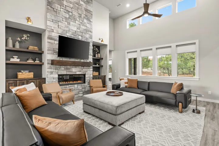 Expansive living area featuring a floor-to-ceiling stone fireplace with a wood-beam mantel and an integrated linear electric fireplace