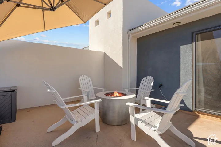 Private outdoor patio featuring a built-in fire pit, privacy walls, and an exterior wall with a sliding glass door