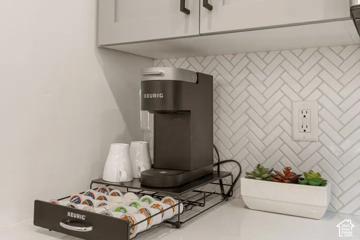 Herringbone tile backsplash with light gray grout, complemented by light gray cabinetry with dark hardware