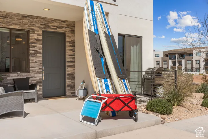 Patio area featuring a stone veneer accent wall, a solid panel entry door, and a sliding glass door