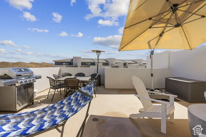 Expansive rooftop terrace featuring a stainless steel grill, a dedicated dining area, and concrete flooring