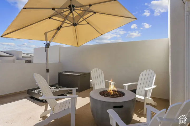 Rooftop patio with a square cantilever umbrella, concrete fire pit, and privacy walls