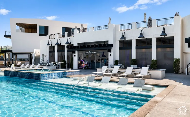 Outdoor swimming pool featuring integrated lounge seating, a separate tiled spa, and a surrounding paver deck
