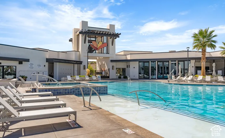 Resort-style pool area featuring a large swimming pool, integrated spa, and surrounding concrete deck