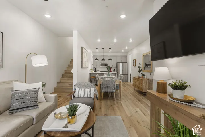 Open-concept living space featuring wood-finish flooring, recessed lighting, and a modern kitchen with stainless steel appliances